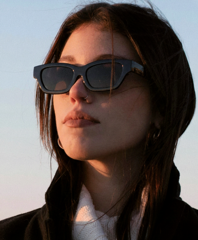 Woman wearing stylish black sunglasses and polarised lenses during sunset.