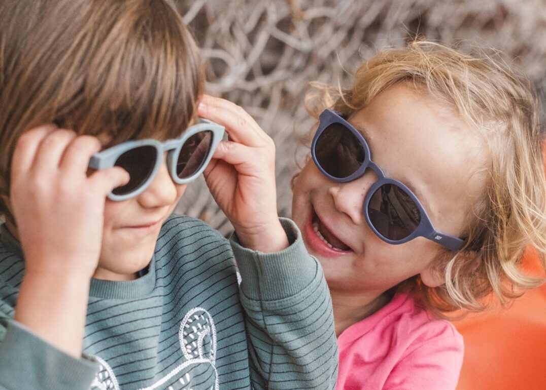 Smiling children with trendy sunglasses from a children's sunglasses wholesaler.