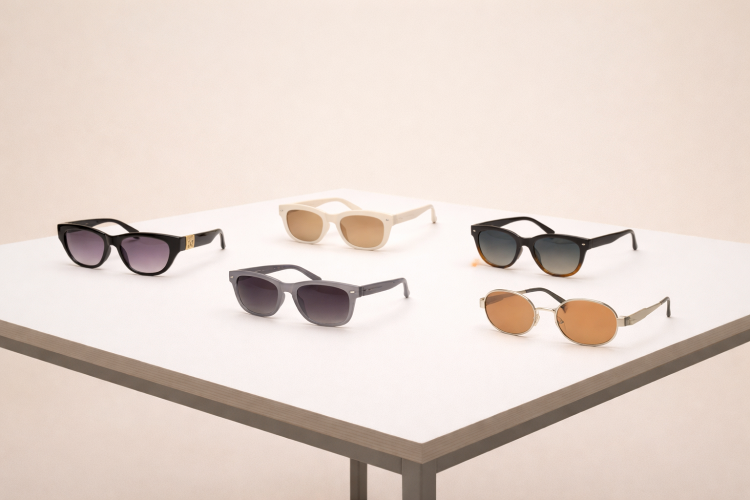 Collection of five different sunglasses on a white table in a minimalist studio setting.